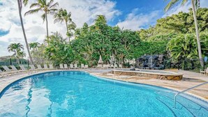 Une piscine avec des chaises longues et des palmiers.