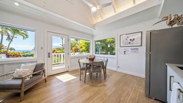 A spacious kitchen with a dining area, large windows with tropical views, and a modern ceiling design.