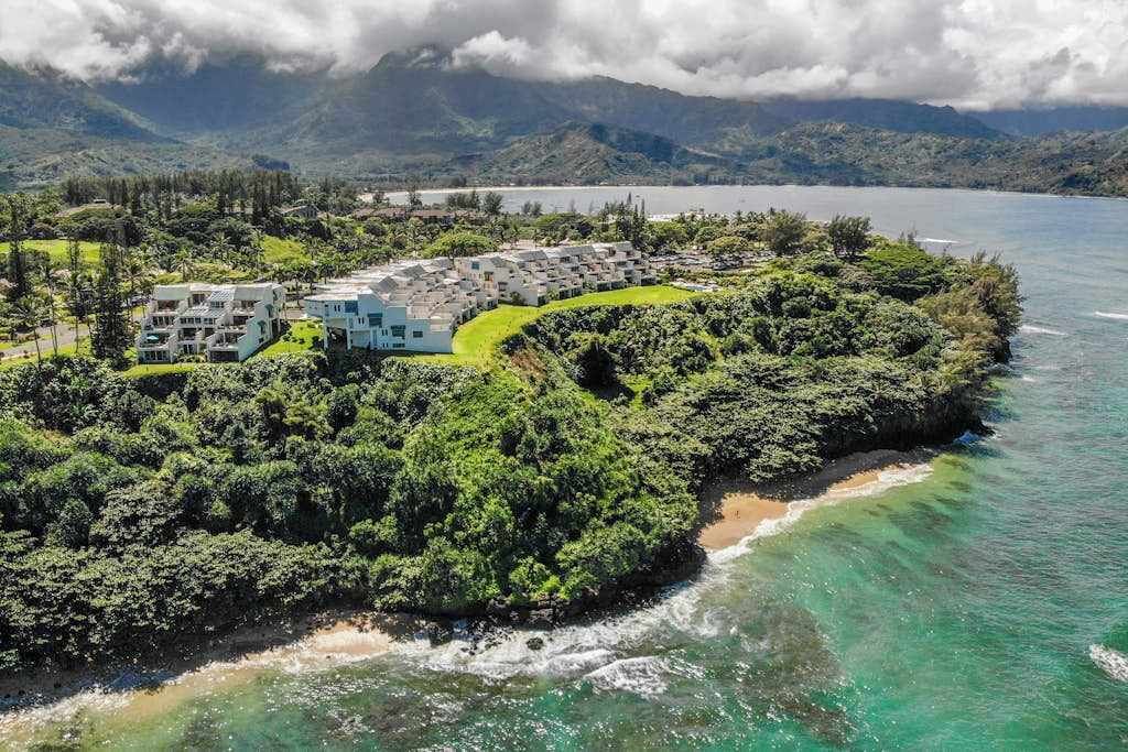 Ein Küstenresort mit Strandlage, üppiger Vegetation und einer Bergkulisse im Hintergrund.