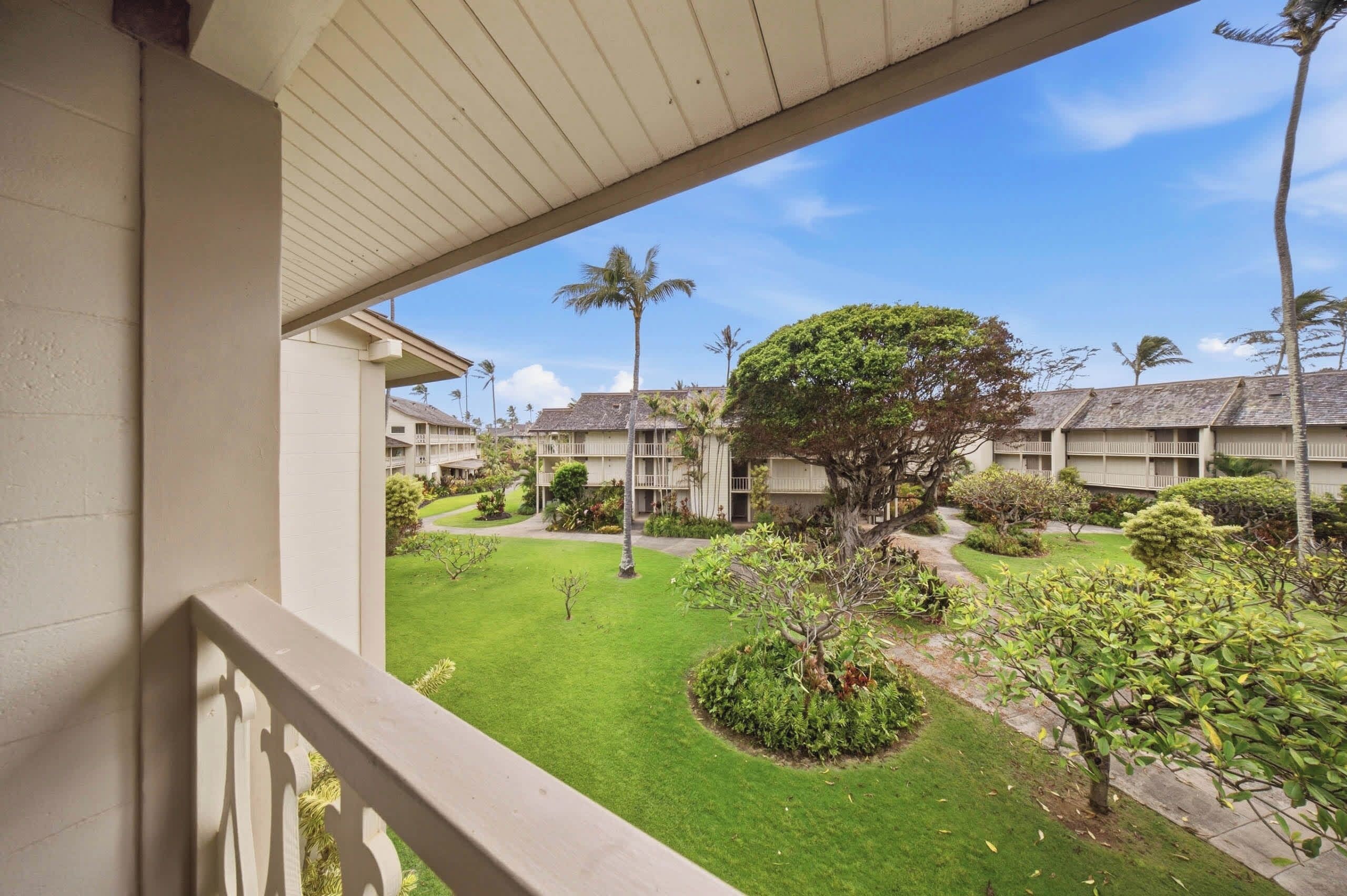 A hotel courtyard with a central lawn, surrounding buildings, and a clear sky.