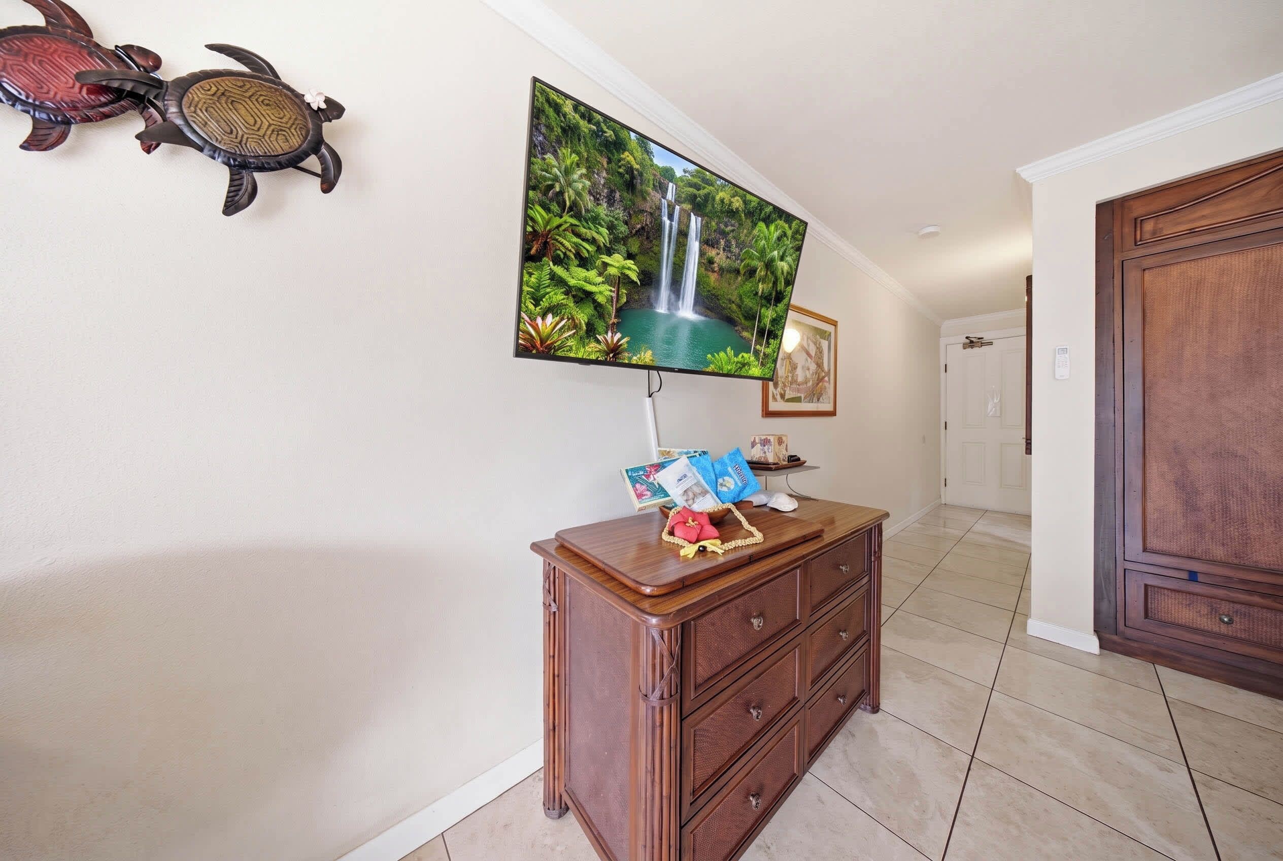 Un couloir avec une armoire en bois, un téléviseur à écran plat fixé au mur et un tableau encadré accroché au mur.