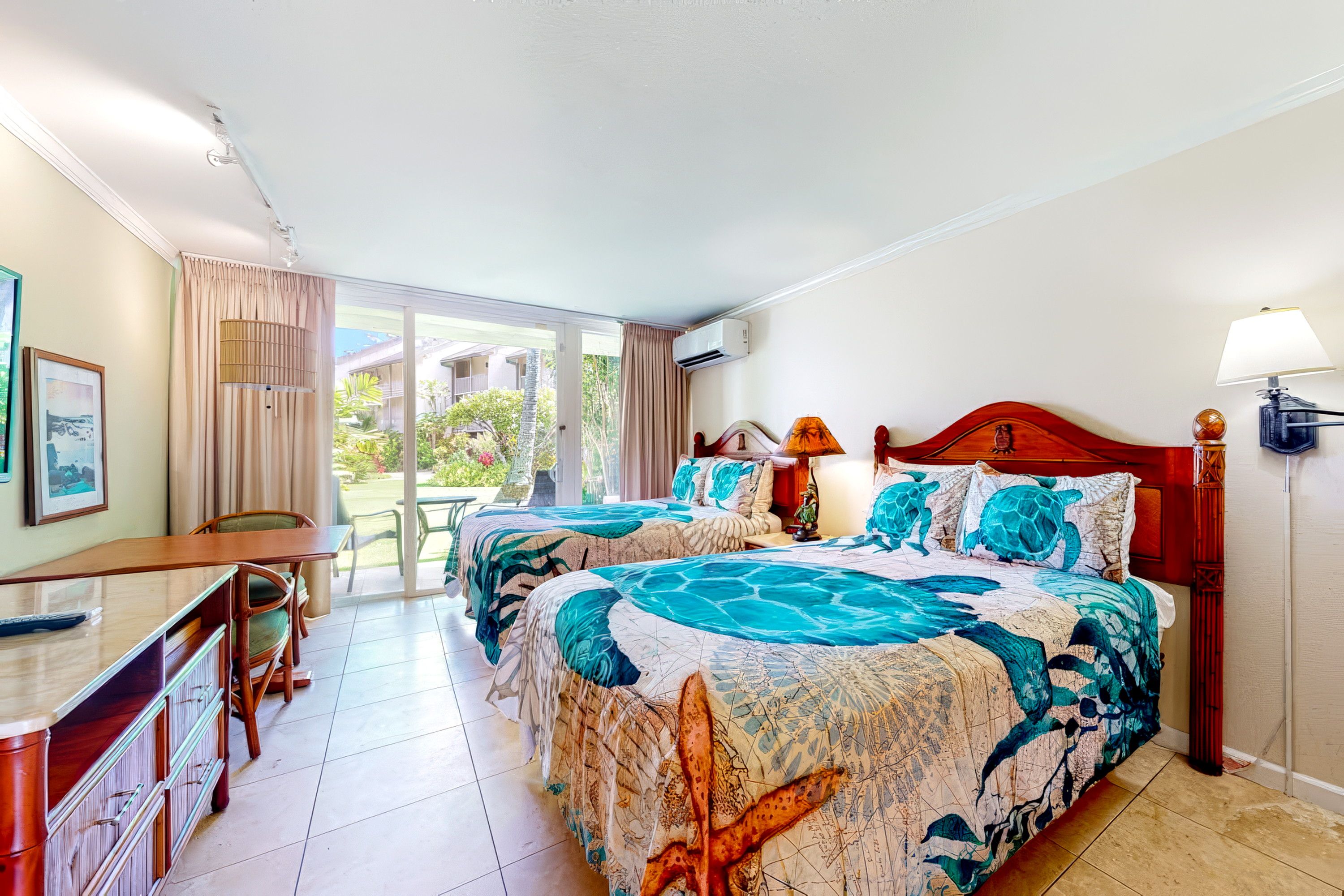 Quarto de hotel com duas camas, uma escrivaninha, uma cadeira e vista para o exterior.