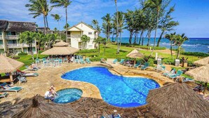 Un resort con una grande piscina, lettini e palme.