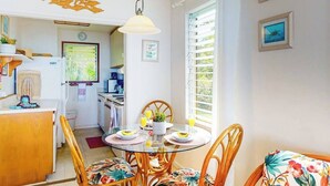 Een eetgedeelte met een ronde tafel, stoelen, een hanglamp en uitzicht op de keuken.