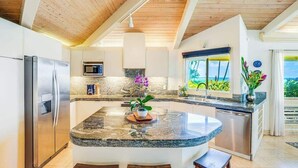 A modern kitchen with a central island, stainless steel appliances, and a view of the outdoors. - *New* Fall Special Poipu Waterfront Home with Athletic Club Perks (Koloa)