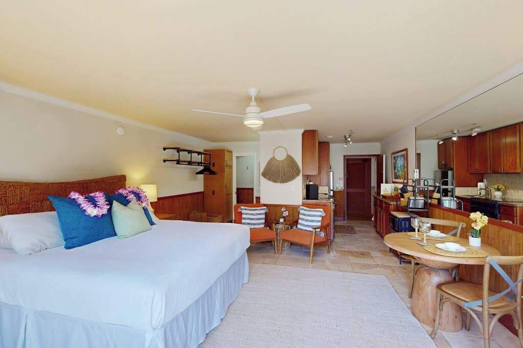 A hotel room with a bed, a dining area, and a kitchenette.