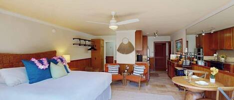 A hotel room with a bed, a dining area, and a kitchenette.