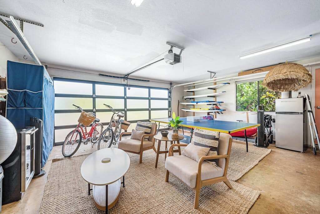Un grand garage aménagé avec une table de ping-pong, un coin salon et des vélos.
