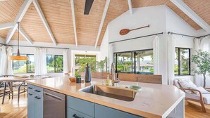 Uma cozinha moderna com uma ilha grande, vigas de madeira no teto e vista para o exterior.