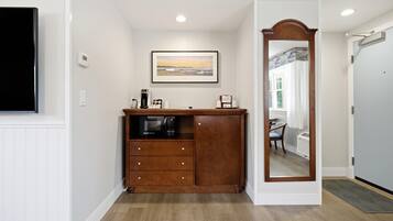 Une chambre d’hôtel avec une commode en bois, un tableau encadré au mur et un miroir avec un cadre en bois.