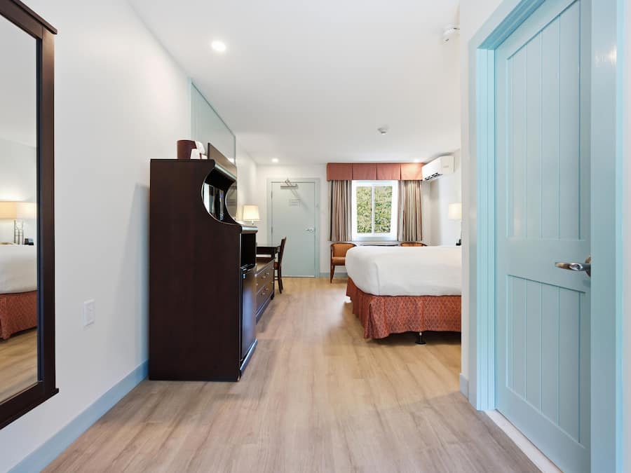 Een hotelkamer met een grote spiegel, een kledingkast, een bureau met stoel en twee bedden.