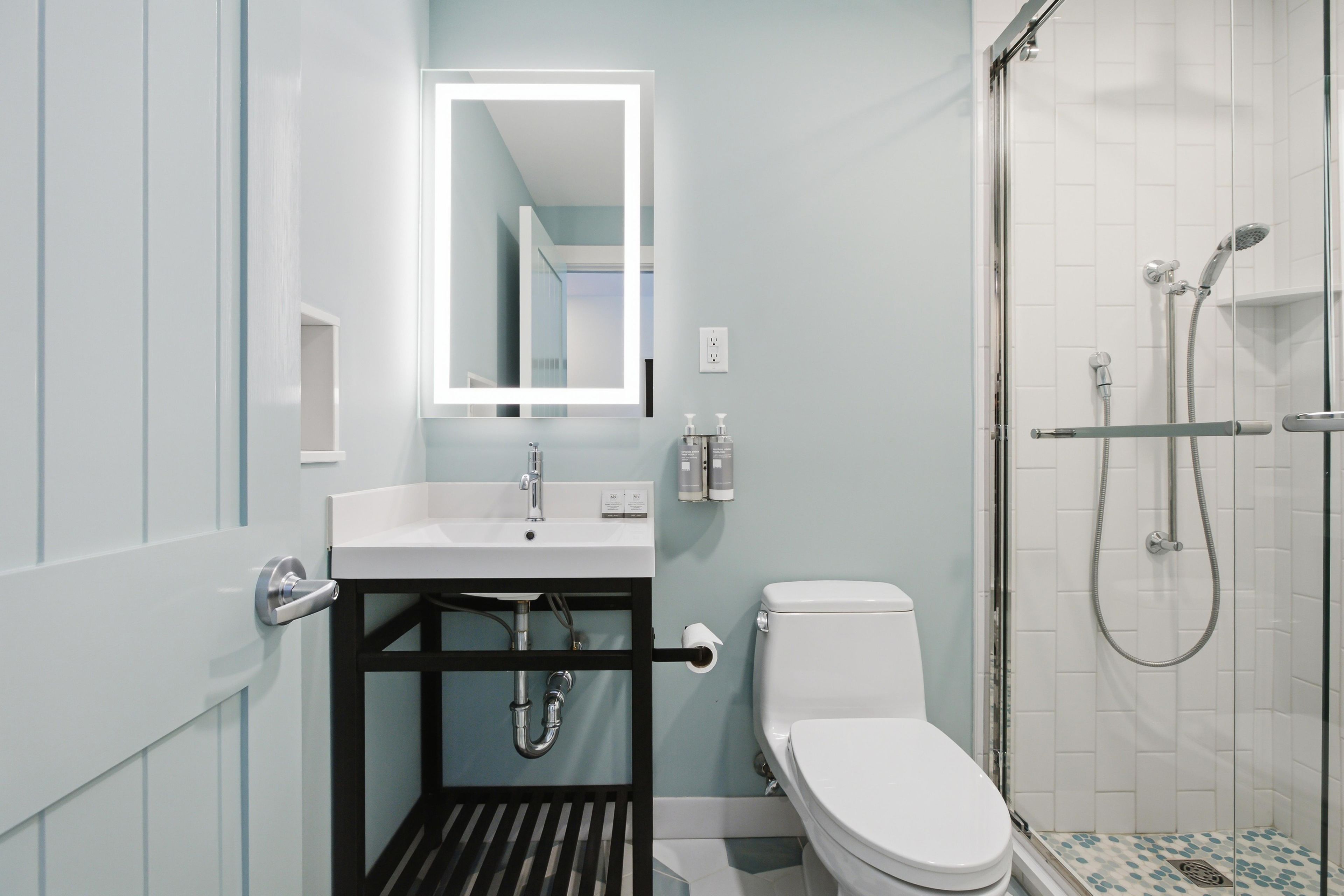 A modern bathroom with a white sink, a toilet, and a shower area.
