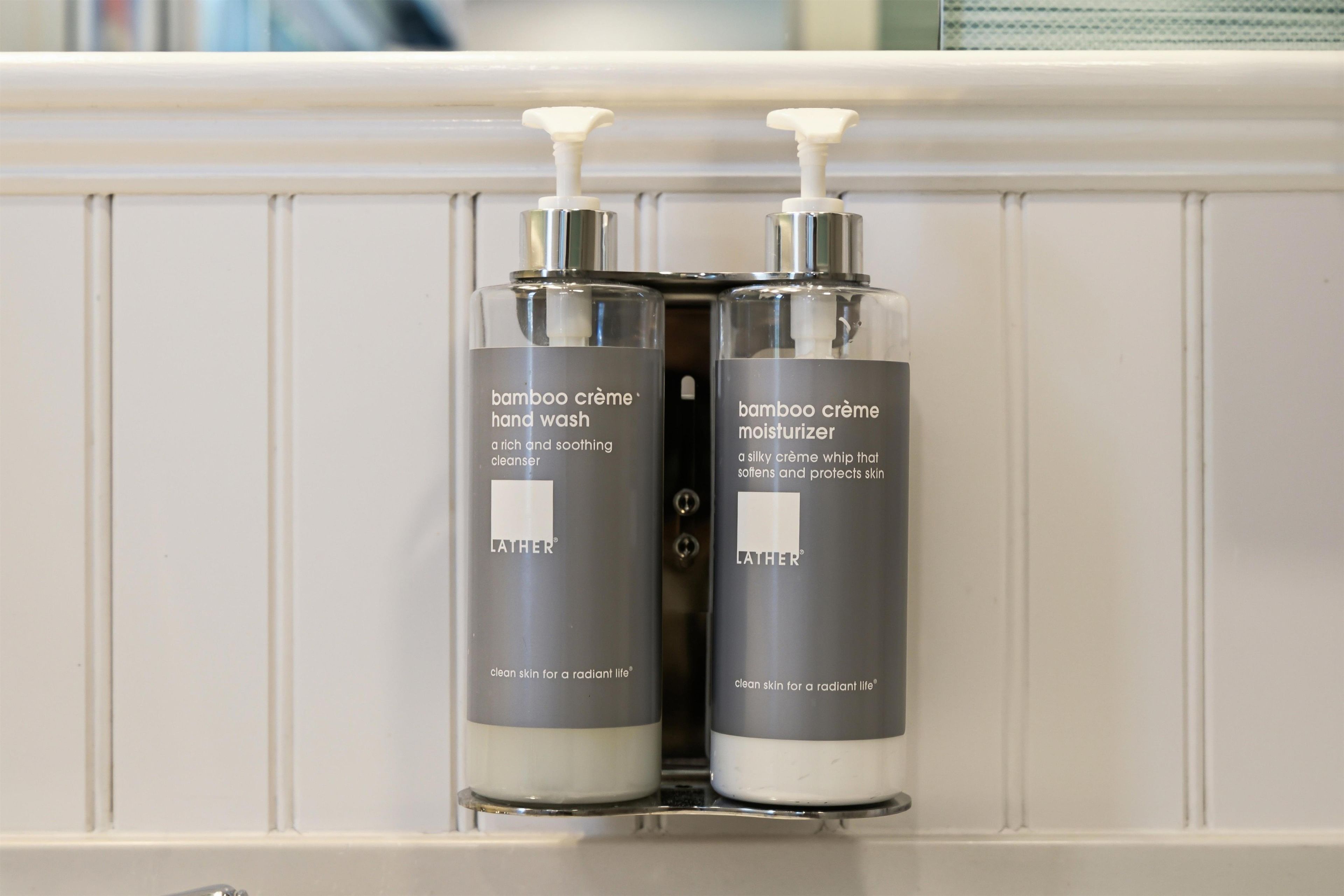 Zwei Flaschen Lather Bamboo Creme Handseife und Feuchtigkeitscreme auf einem weißen Regal.