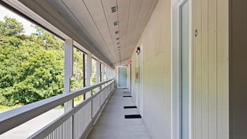 A corridor with a railing, a fire exit sign, and a door with a number.