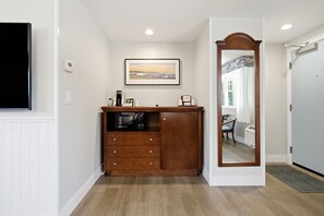 Une chambre d’hôtel avec une commode en bois, un tableau encadré au mur et un miroir avec un cadre en bois.