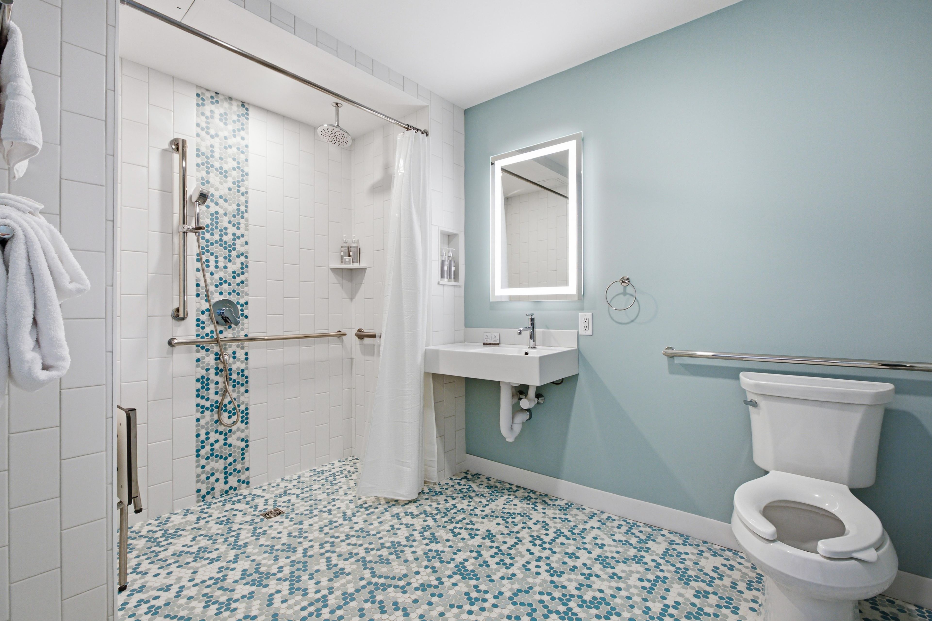 A bathroom with a shower, toilet, sink, and a mirror.