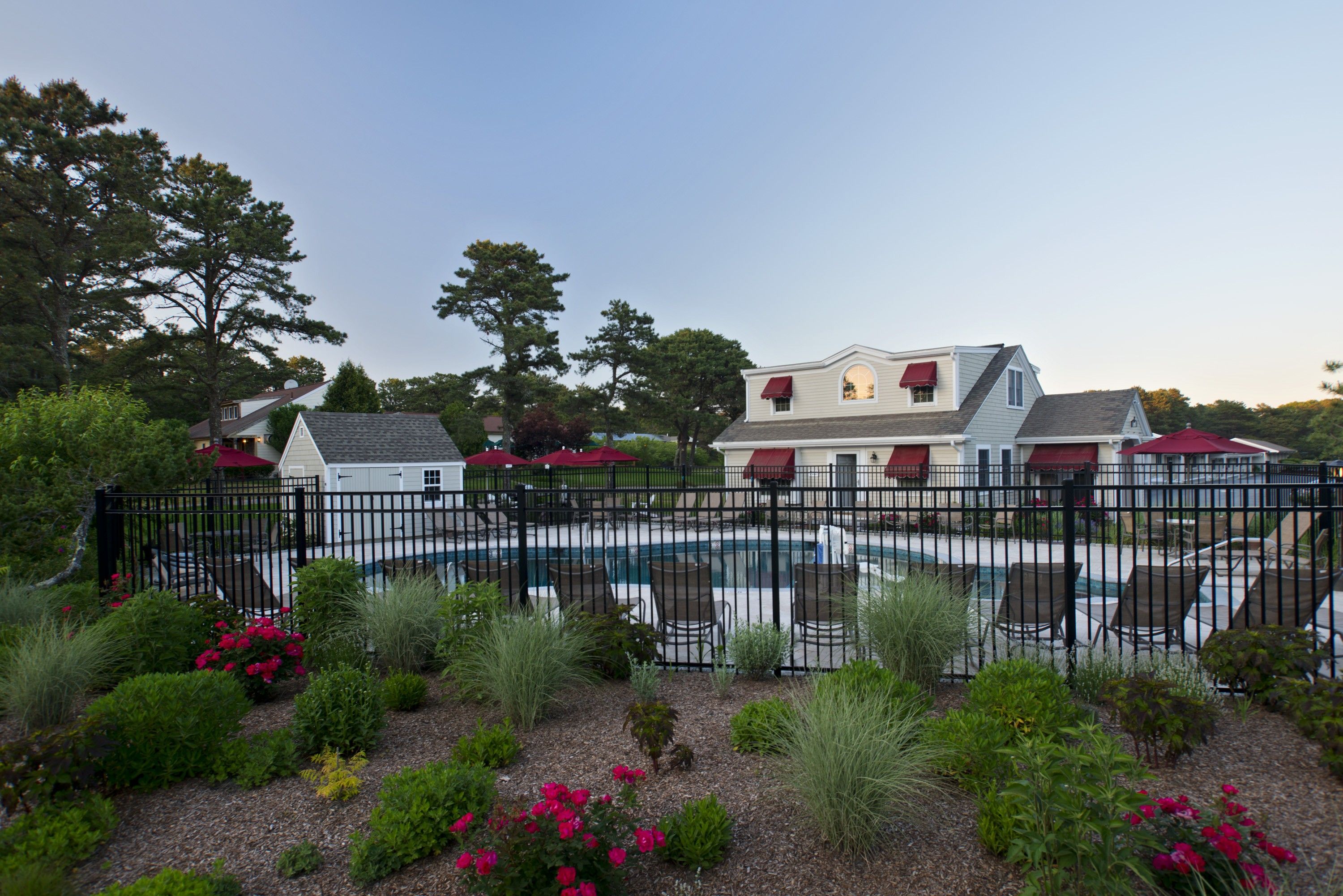 A residential property with a swimming pool, surrounded by a fence and various plants.