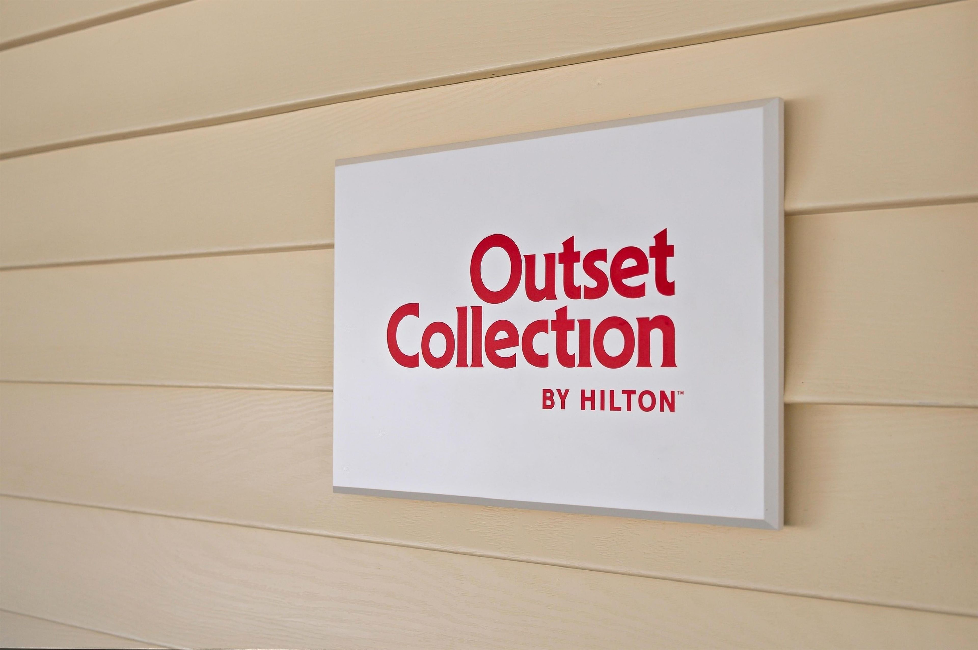 A sign with the text 'Outset Collection by Hilton' on a beige wall.
