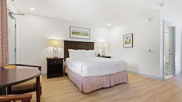 Quarto de hotel com cama, mesas de cabeceira, uma cadeira e um quadro na parede.