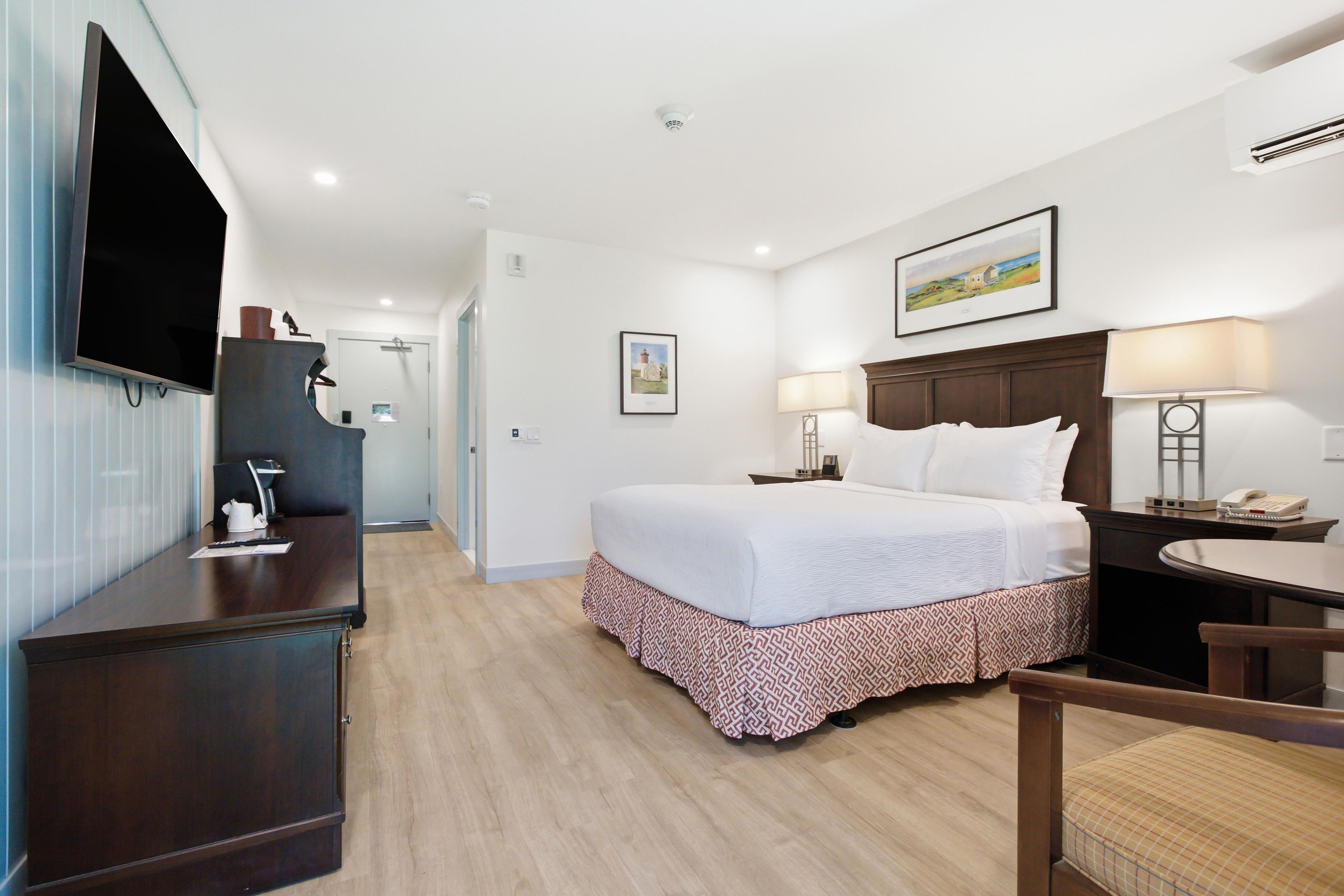 A hotel room with a bed, desk, chair, and a television.