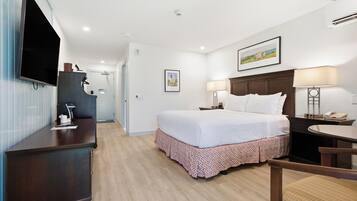A hotel room with a bed, desk, chair, and a television.
