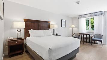 Une chambre d’hôtel avec un grand lit, des lampes de chevet, un bureau avec une chaise et une fenêtre avec des rideaux.