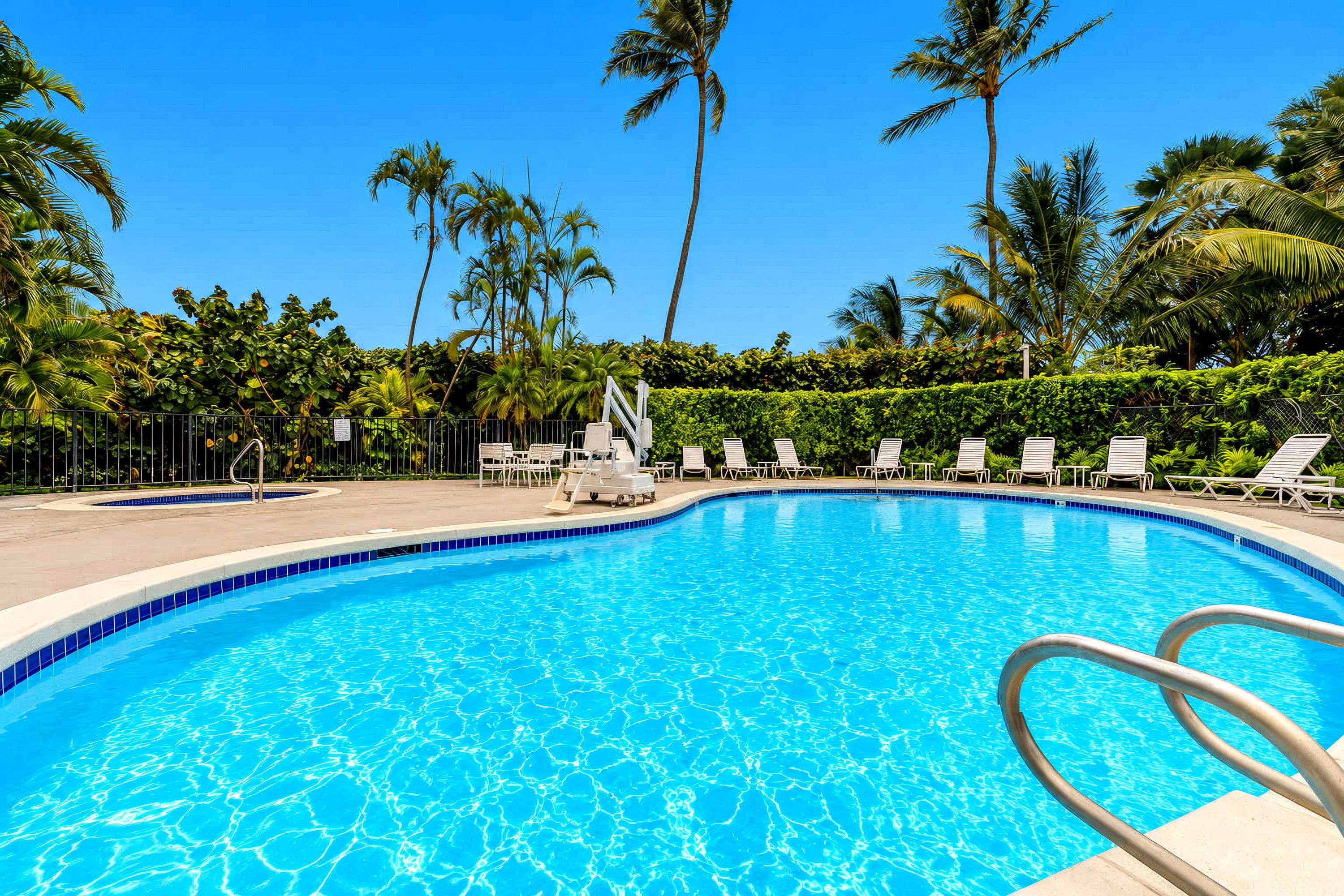 Une piscine d’un bleu éclatant, entourée de palmiers et de chaises longues.