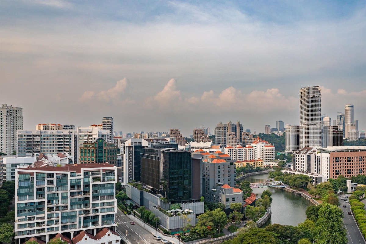 A cityscape with modern buildings, a river, and a bridge.