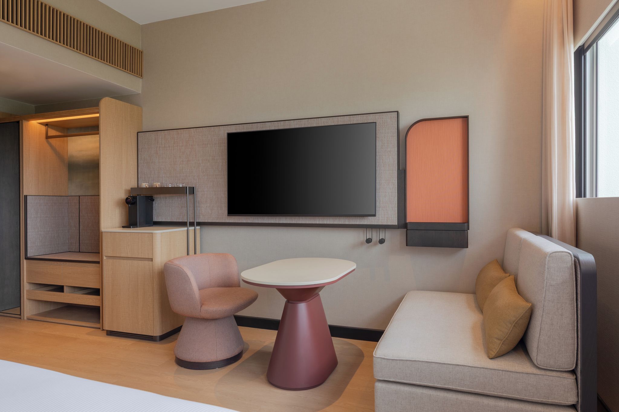 A modern room with a sofa, a table, a TV, and a coffee machine.