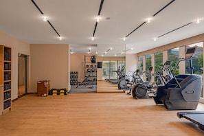 Un gimnasio con equipo de ejercicio, un estante para pesas y un espejo.