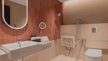 Un baño moderno con un espejo grande, un lavamanos, una ducha y un inodoro.
