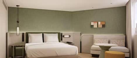 A modern hotel room with a large bed, a bedside table, a sofa, and a small table.