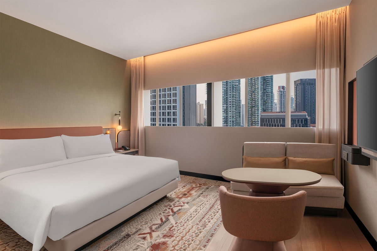 A hotel room with a large bed, a sofa, a small table, and a TV.
