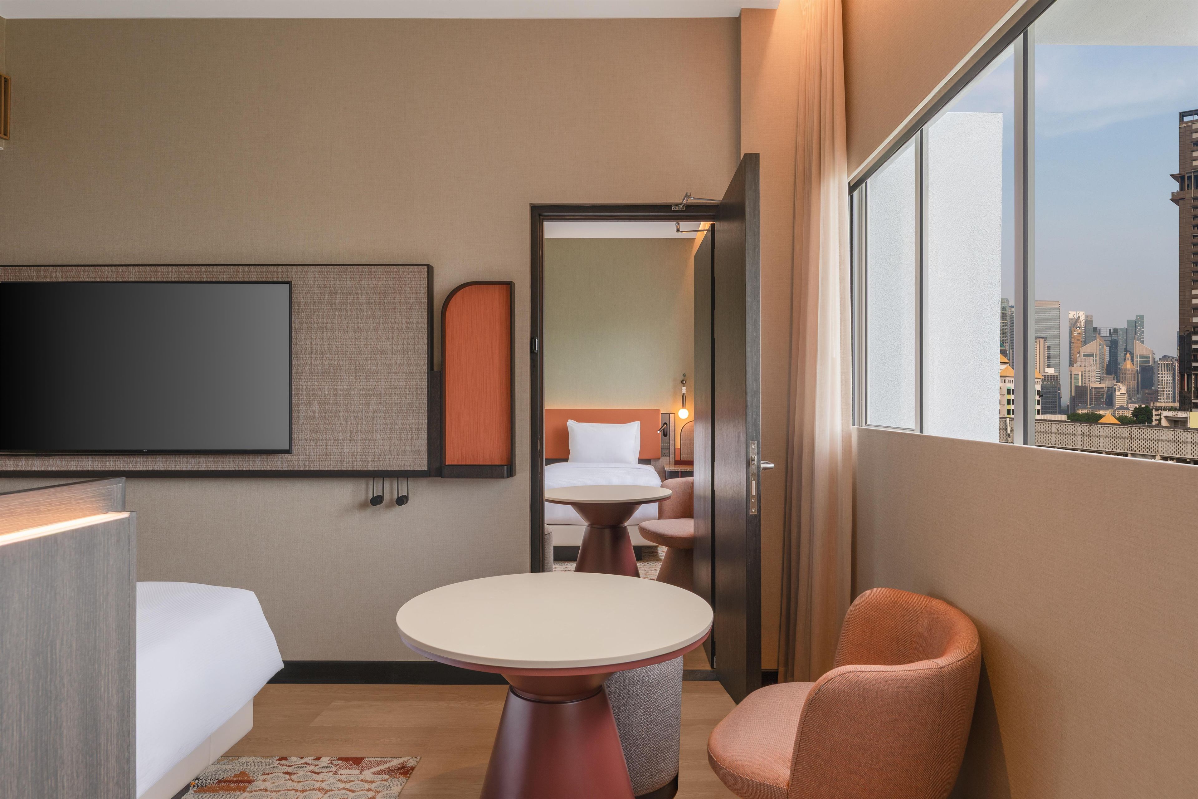 Una habitación de hotel con cama, televisión, una mesita y una silla.