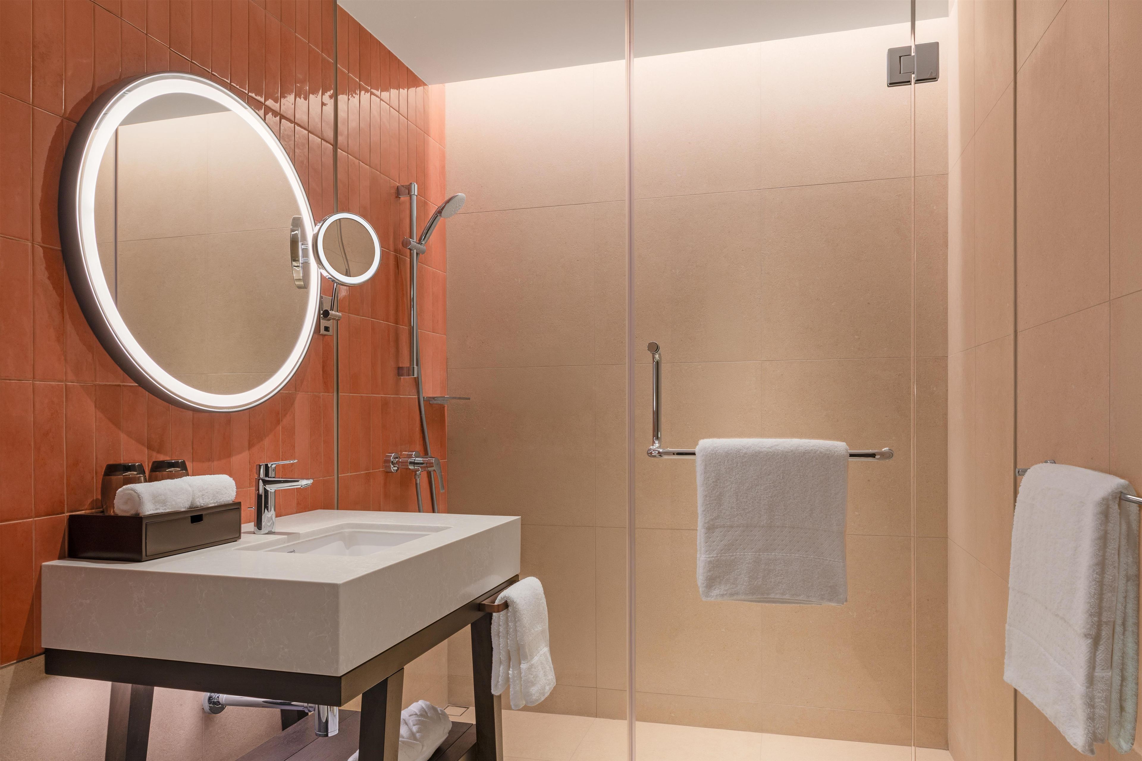 A modern bathroom with a vanity, a mirror, a shower, and a towel rack.