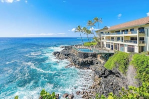 A hotel with a pool, palm trees, and a view of the ocean. - New Oceanfront Poipu Townhome with Lanai and Heated Pool (Poipu)