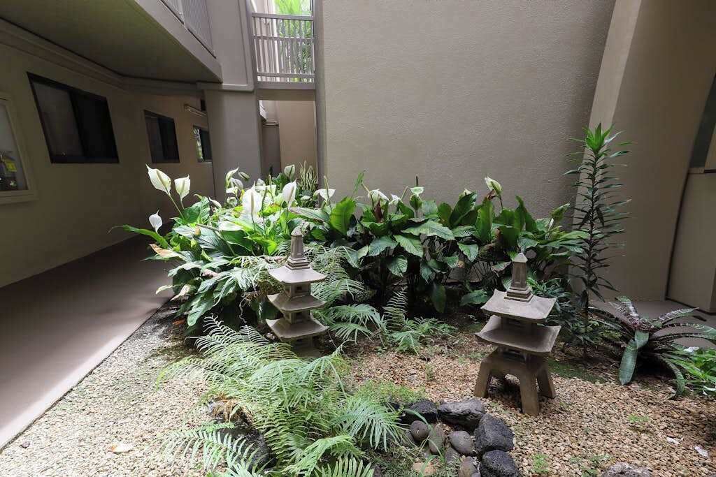 Une cour agrémentée d’une lanterne en pierre, d’une végétation luxuriante et d’un petit jardin de rochers.