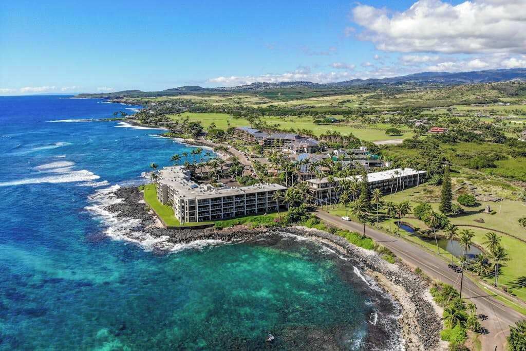 A coastal resort with a large building, a beach, and a golf course.