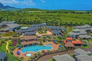 Un resort con varias edificaciones, una piscina central y abundante vegetación.