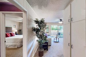 A hallway leading to a bedroom with a bed, a potted plant, a sofa, and a dining area. - NEW Fall Sale Cool-Off Pools and Coconut Coast Days in Kapaʻa (Kapaa)