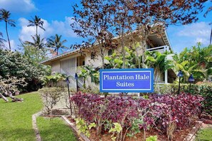 A sign for 'Plantation Hale Suites' with a garden and palm trees in the background. - NEW Fall Sale Cool-Off Pools and Coconut Coast Days in Kapaʻa (Kapaa)