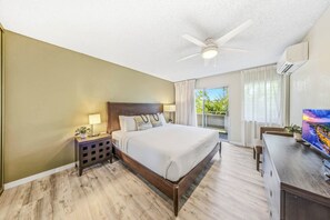 Ein Hotelzimmer mit Bett, Schreibtisch, Deckenventilator und einem blickdichten Fenster.