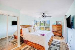 A bedroom with a bed, a ceiling fan, a TV, and a window with blinds. - NEW Fall Deal Water-View Lihue Condo Steps from the Beach (Lihue)