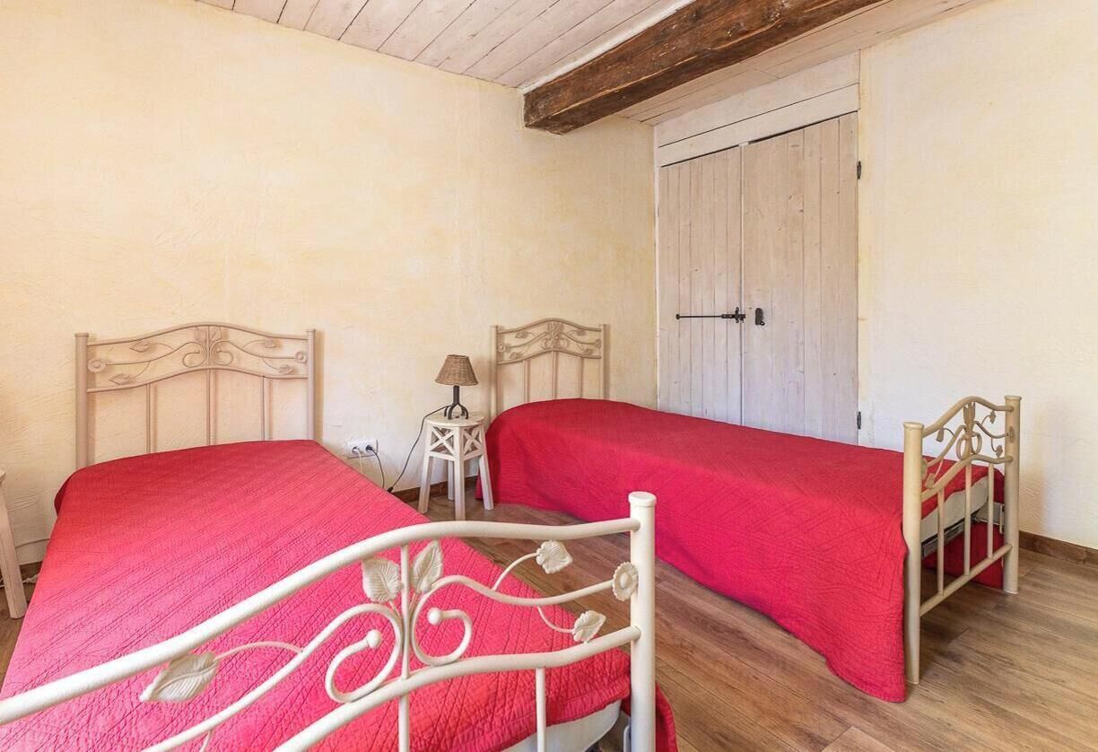 Een slaapkamer met twee bedden, een houten deur en een klein nachtkastje met een lamp.
