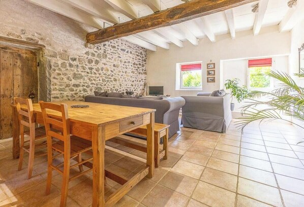 Un intérieur rustique avec un mur en pierre, des meubles en bois et un sol carrelé.