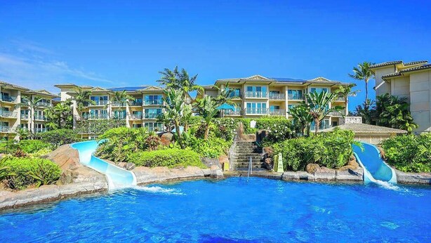 Un resort con piscina, tobogán de agua y edificios de varios pisos con balcones.