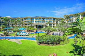 A hotel with a swimming pool, lounge chairs, and a waterfall. - *NEW* Oceanfront Resort Living Near Kapa'a's Beach and Shops (Kapaa)
