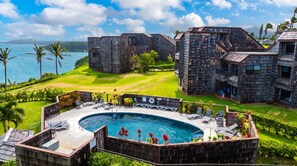 A modern resort with a pool area, multiple buildings, and a view of the ocean. - Oceanfront Sealodge Condo at Princeville w/ Kitchen, Essentials, Beach, Shopping (Princeville)
