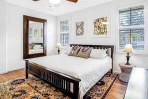 A bedroom with a large bed, a mirror, two wall-mounted lamps, and a window with blinds. - *New* Two-Story Princeville Family Escape with Pool and AC (Princeville)