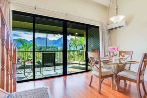 Une pièce dotée d’une grande porte-fenêtre coulissante donnant sur un balcon avec vue sur les montagnes et la verdure.
